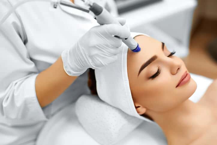 Aesthetician performing a microdermabrasion treatment on a client